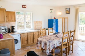 A kitchen with wooden cabinets, a washing machine, a blue refrigerator, and a dining table with chairs.