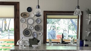 A kitchen with a large island, two bar stools, hanging pendant lights, and a wall of decorative plates. - Charming Mountain Cottage. (Pine Valley)