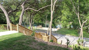 A backyard with a wooden deck, a small pond, and a grassy area with trees. - "The Penthouse" #2 right on the Guadalupe, sleeps up to 15 people-private access (New Braunfels)