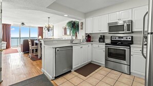 A modern kitchen with white cabinets, stainless steel appliances, and a view to the outside. - Hot Tub, Pools, Wifi, Oceanfront, 7th Floor, AshWorth | AshWorth - 706 (North Myrtle Beach)