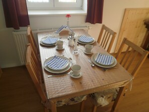 A dining table set with blue and white checkered napkins, plates, cups, and cutlery.
