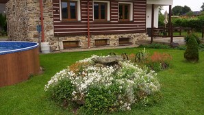 Una casa de dos pisos con fachada de piedra, terraza de madera y piscina.
