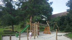 Un parque infantil con tobogán, muro de escalar y columpios.