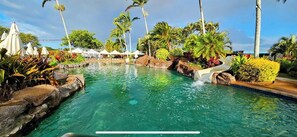 A clear pool with a water slide, surrounded by palm trees and tropical plants. - 2/2 BEACHFRONT RESORT w AC, Poipu Beach - Kiahuna Garden View Condo, Pool/Gym (Koloa)