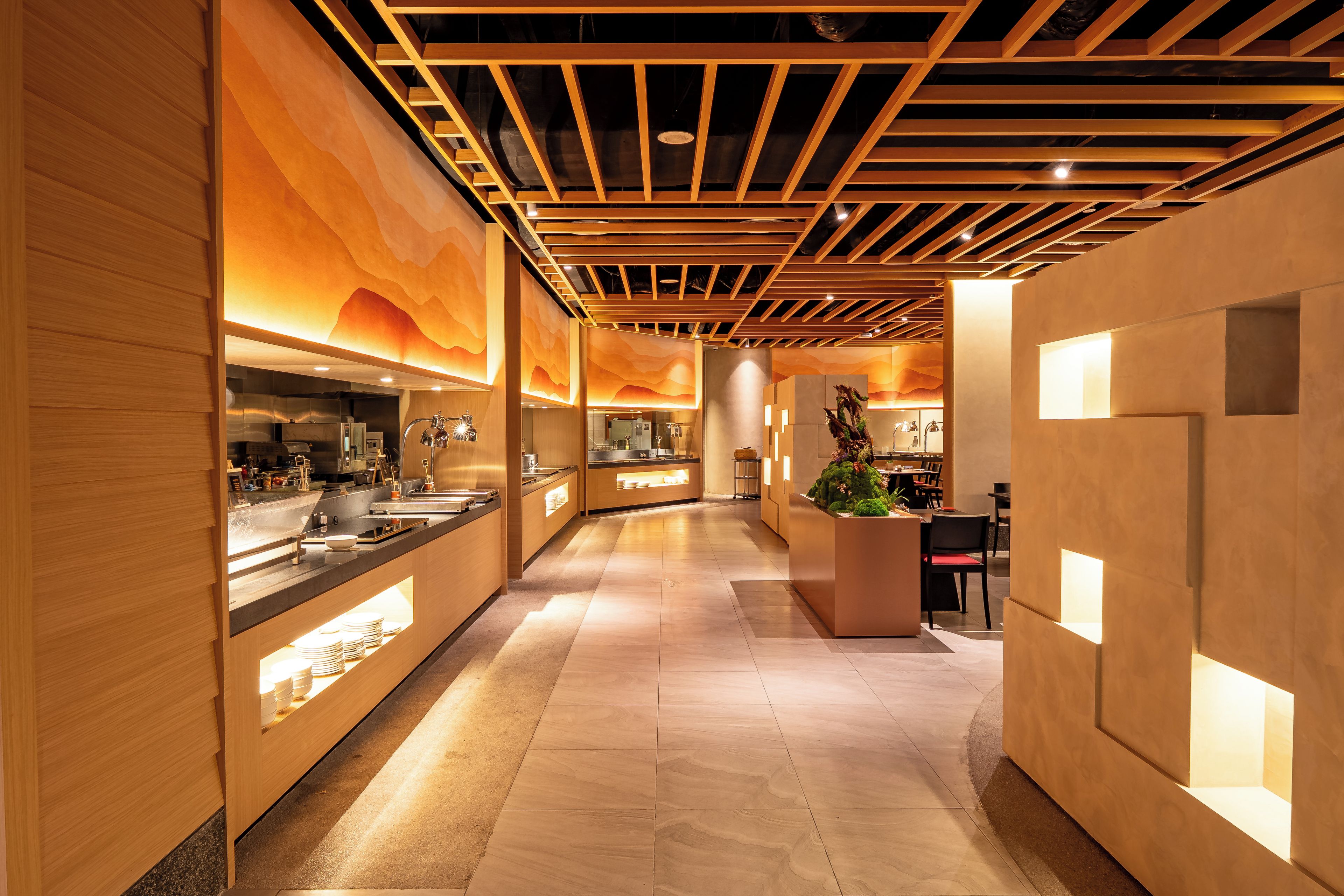 A modern hotel lobby with a long reception desk, wooden paneling, and a central decorative feature.