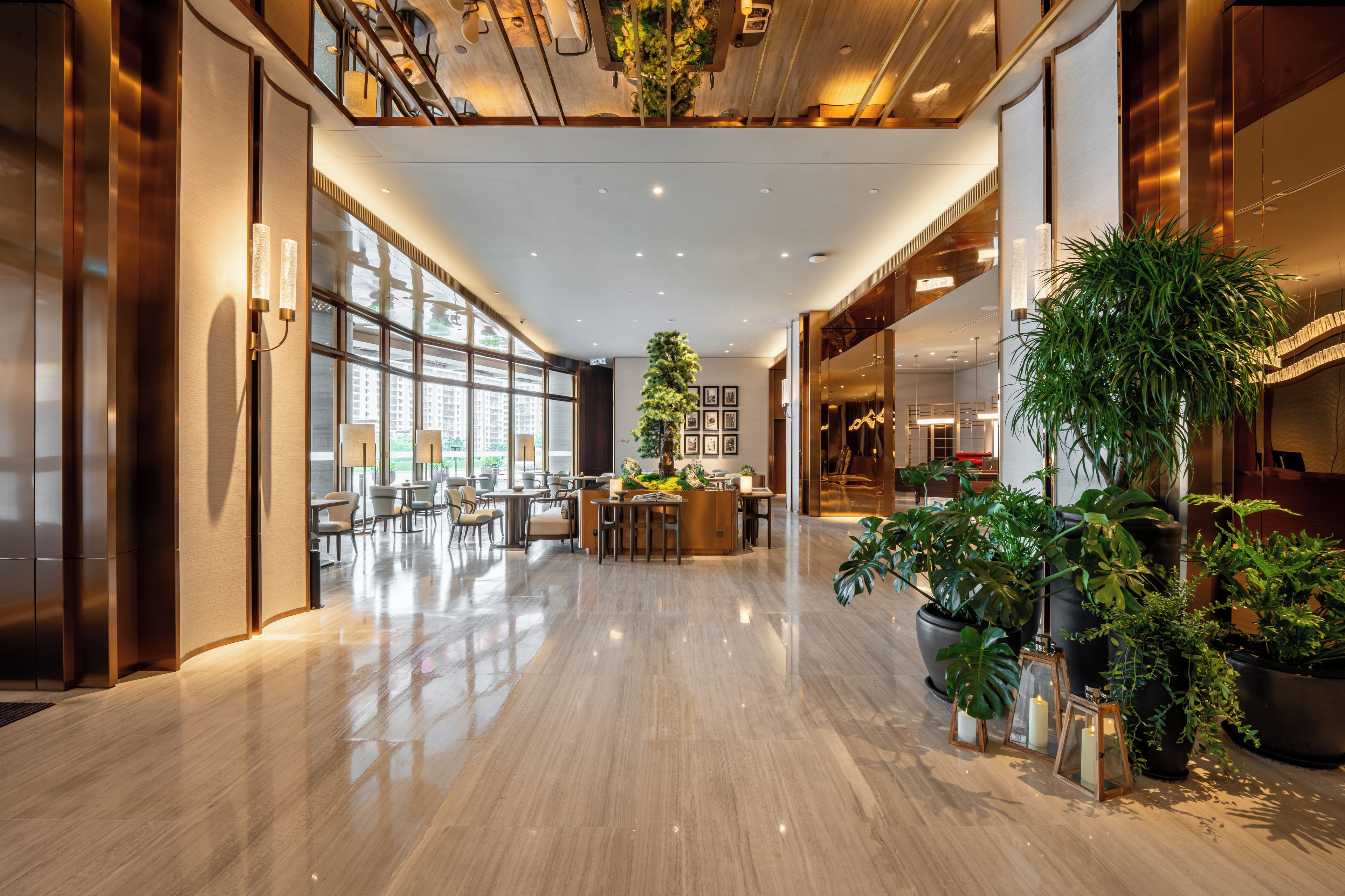 A spacious hotel lobby with a high ceiling, large windows, and a central seating area.
