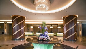 A lobby with a central round table, two large wooden pillars, a reception desk, and a chandelier. - St. Giles Mid Valley Kuala Lumpur (Kuala Lumpur)