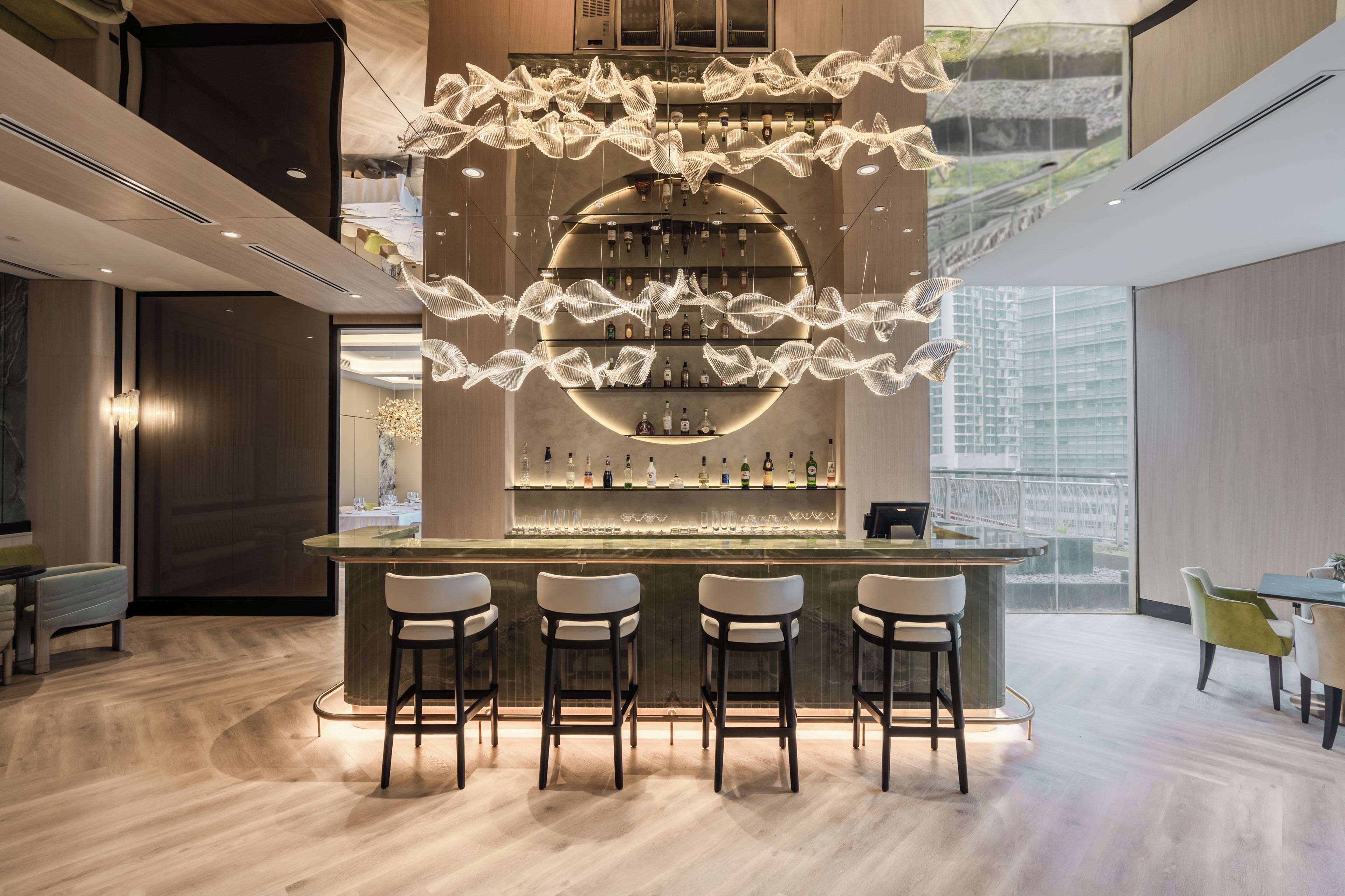 A modern bar area with a central light fixture, bar stools, and a wine rack.
