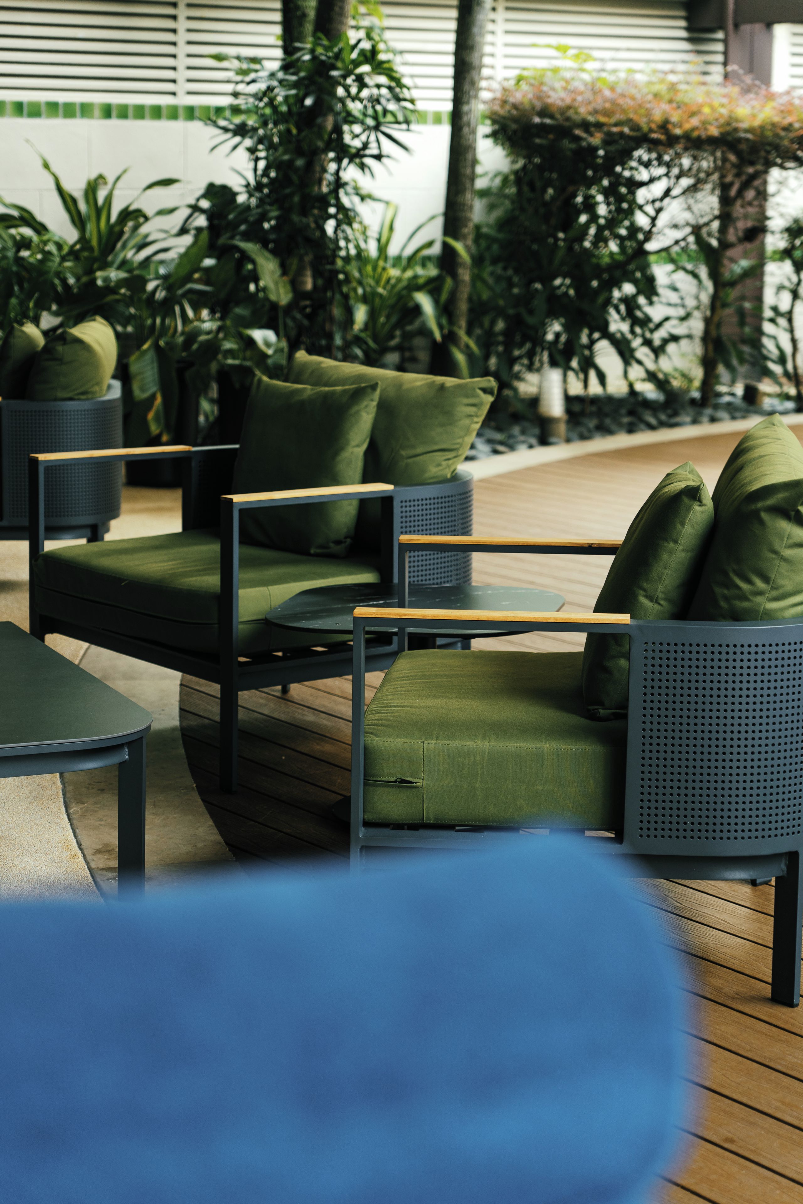 An outdoor seating area with a sofa and chairs, surrounded by potted plants.