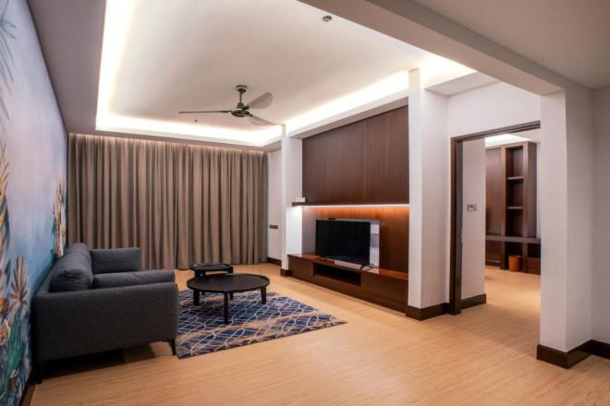 Una sala de estar moderna con sofá, una mesa de centro, televisor y ventilador de techo.