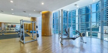 A spacious gym with exercise equipment, large windows, and a modern design.
