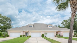 A two-story house with a garage, a driveway, and a well-maintained lawn. - 3BR Golf Course Townhome | Community Pool, Full Kitchen & In-Unit Laundry (New Smyrna Beach)