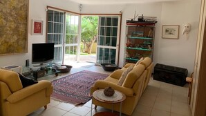 A living room with a sofa, a television, a glass coffee table, and a bookshelf. - Situada dentro de um condomínio fechado de luxo, com a praia a 3 minutos a pé (Porto Santo)