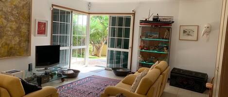 A living room with a sofa, a television, a glass coffee table, and a bookshelf.