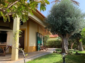 Ein Haus mit überdachter Terrasse, Gartenmöbeln im Freien und einem gepflegten Garten.