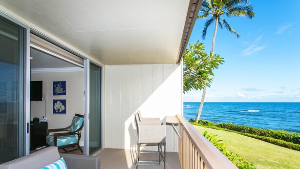 A balcony with a view of the ocean, a sofa, a chair, and a small table. - H-G-T-V type Renovation, Million Dollar view starting at only $210/night! (Kapaa)