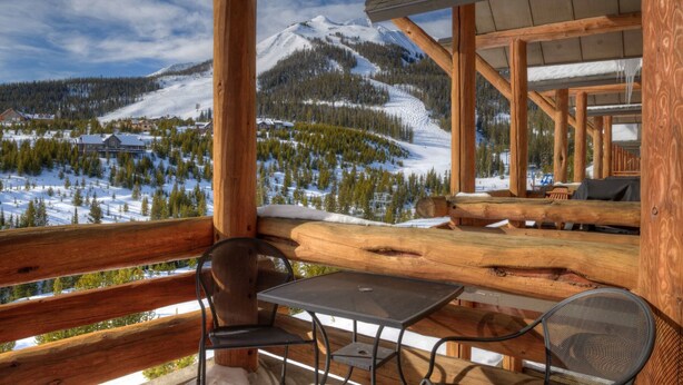 A wooden cabin with a balcony overlooking a snowy mountain landscape. - True Ski-in/ski-out Saddle Ridge Townhome - private hot tub, new bathrooms (Big Sky)
