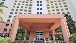 A hotel entrance with a large, open lobby, a central staircase, and a modern building facade with a grid pattern.