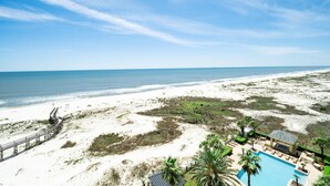 A beach resort with a wooden boardwalk, a pool area, and a view of the ocean.