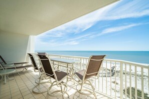 Varanda com mesa e cadeiras com vista para a praia.
