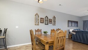 Uma sala de jantar com mesa e cadeiras de madeira, um pequeno vaso com planta e arte decorativa na parede.