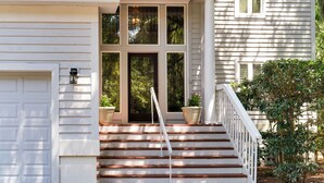 Ein Haus mit Veranda, Treppe und Garagentor.