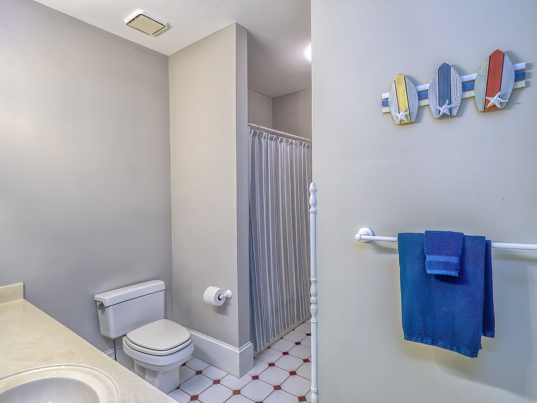 A bathroom with a toilet, shower, and a towel rack with a blue towel.