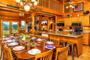 A wooden cabin with a dining area, kitchen, and a view of the mountains.