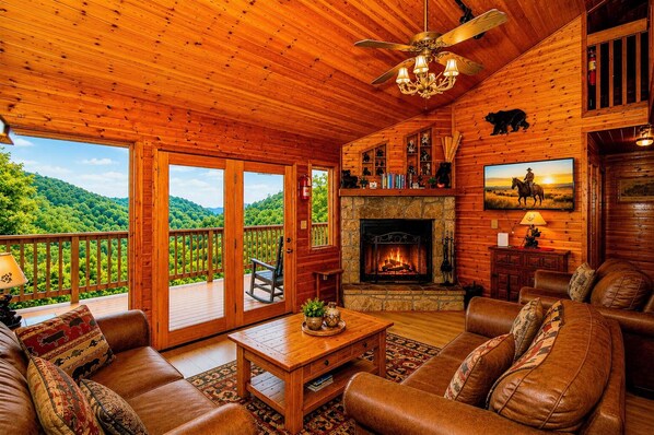 A log cabin interior with a fireplace, leather furniture, and a balcony with a scenic view.
