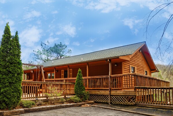 A wooden cabin with a porch, surrounded by greenery. - Amazing Views!  > Dollywood, Hot Tub, Theater, Games, Resort Pool, Pet Friendly (Gatlinburg)