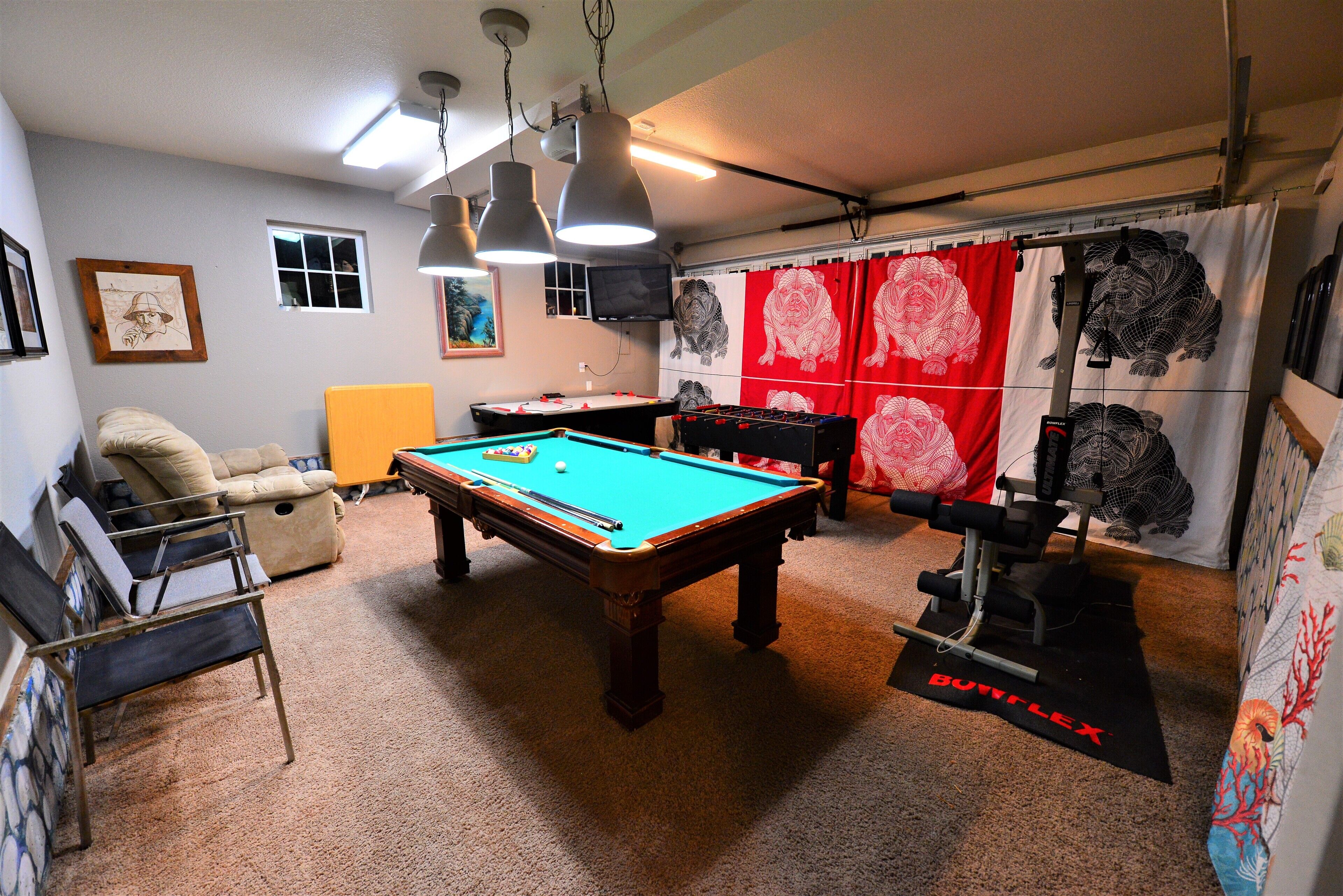 Een kamer met een pooltafel, een bank en een tafelvoetbal.