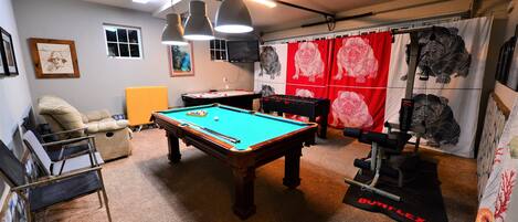 Een kamer met een pooltafel, een bank en een tafelvoetbal.