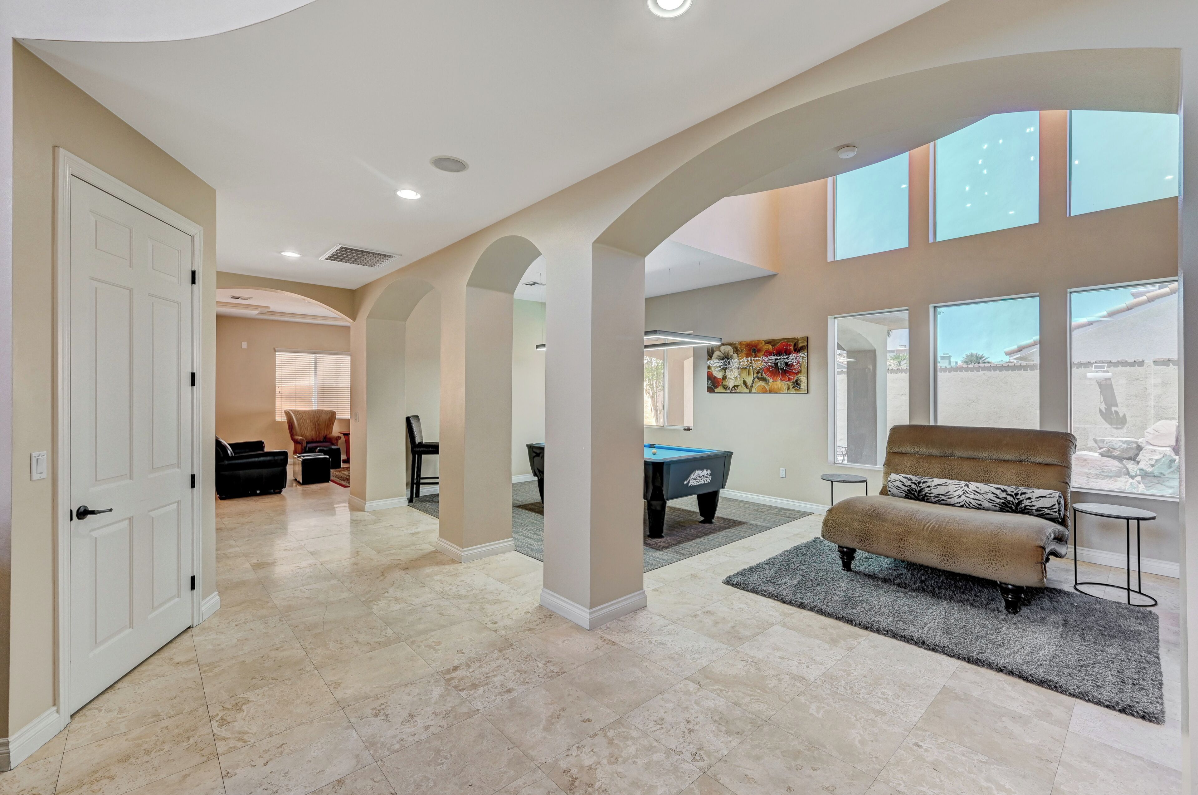A spacious living area with a pool table, a sofa, and a large window with a view.