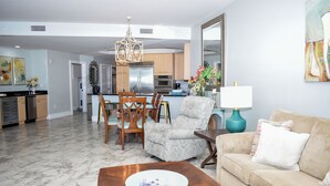A living room with a wooden coffee table, a beige sofa, and a dining area with wooden chairs and a chandelier.