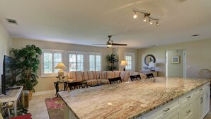 A spacious kitchen with a large island, a dining area with a sofa, and a ceiling fan.