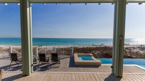 Terraza de madera con sillones de descanso y jacuzzi con vista a la playa.