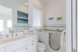 A bathroom with a white sink, a toilet, and a bathtub. There are decorative fish paintings on the wall. - Stunning Gulf-Front Getaway!  Private Beach & Infinity Pool (Miramar Beach)