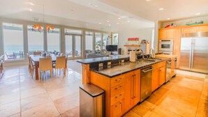 Una cocina amplia con una isla grande, electrodomésticos modernos y vistas al océano.