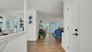 A hallway with a wooden floor, white walls, and a white door on the right. There are two blue turtle wall art pieces on the left wall.