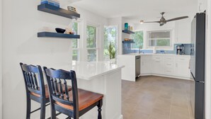 A modern kitchen with white cabinetry, a central island, and a dining area with two chairs.