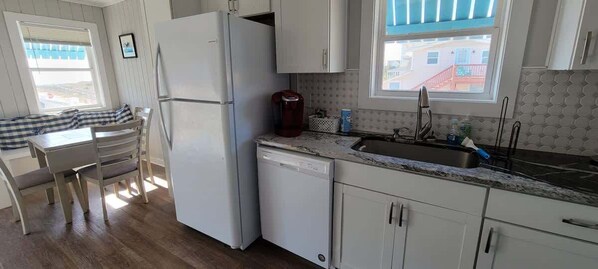 Uma cozinha compacta com geladeira, lava-louças e uma janela com vista.