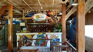 A rustic bar area with a 'Bang Out' sign, wooden beams, and a colorful mural. - HangOut Beach & Resort (Malay)