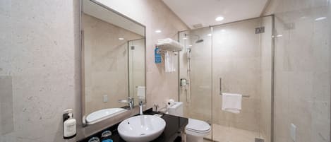 A modern bathroom with a large mirror, a sink, a toilet, and a glass-enclosed shower.