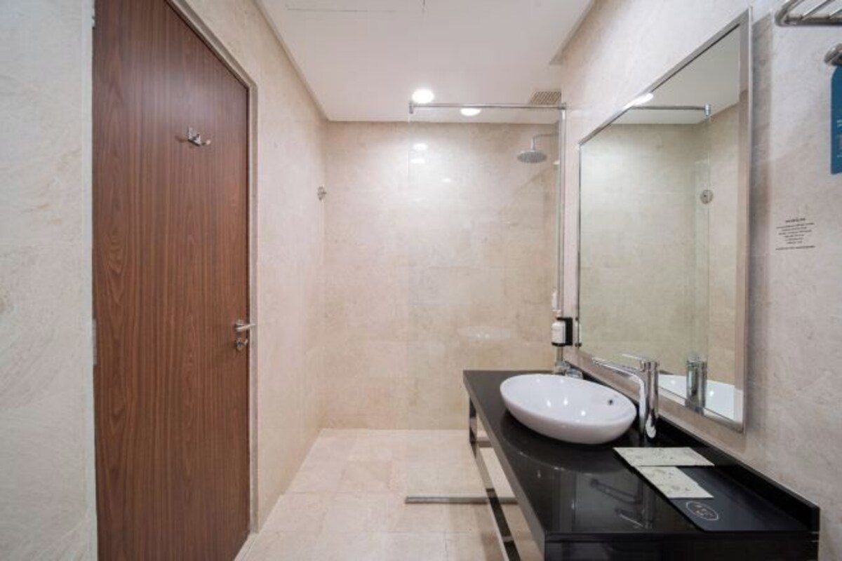 Une salle de bain moderne avec une porte en bois, un lavabo blanc et un grand miroir.