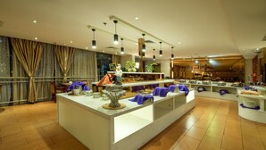 Een moderne hotelentree met een centraal receptiegedeelte, een groot raam met gordijnen en een bar met diverse voorzieningen.