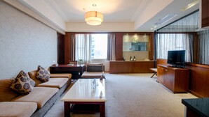 Een moderne hotelkamer met een zithoek, een zettel, een eettafel, een televisie en een minibars.