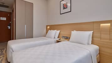 A hotel room with two beds, a wooden headboard, a bedside table with a phone, and a framed picture on the wall.