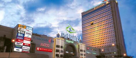 Un hotel con un llamativo letrero que dice 'Mid Valley', rodeado de varios edificios comerciales y una gran pantalla publicitaria digital.