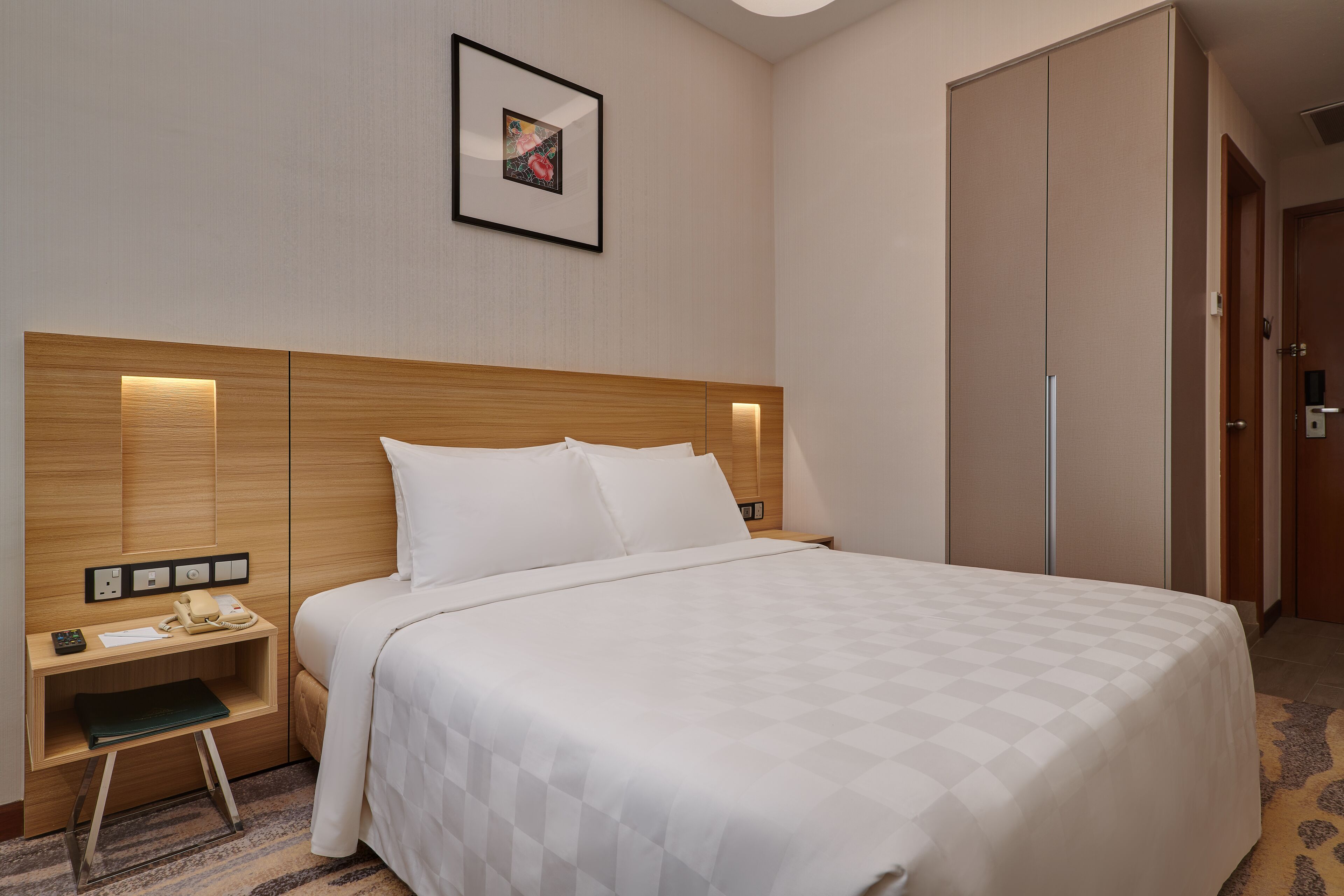 Une chambre d’hôtel avec un grand lit, une table de chevet avec une lampe, une petite table et une armoire.