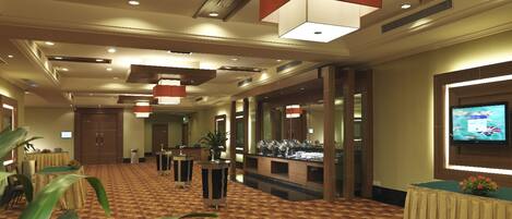 A hotel lobby with a checkered carpet, multiple tables, and a television screen on the wall.